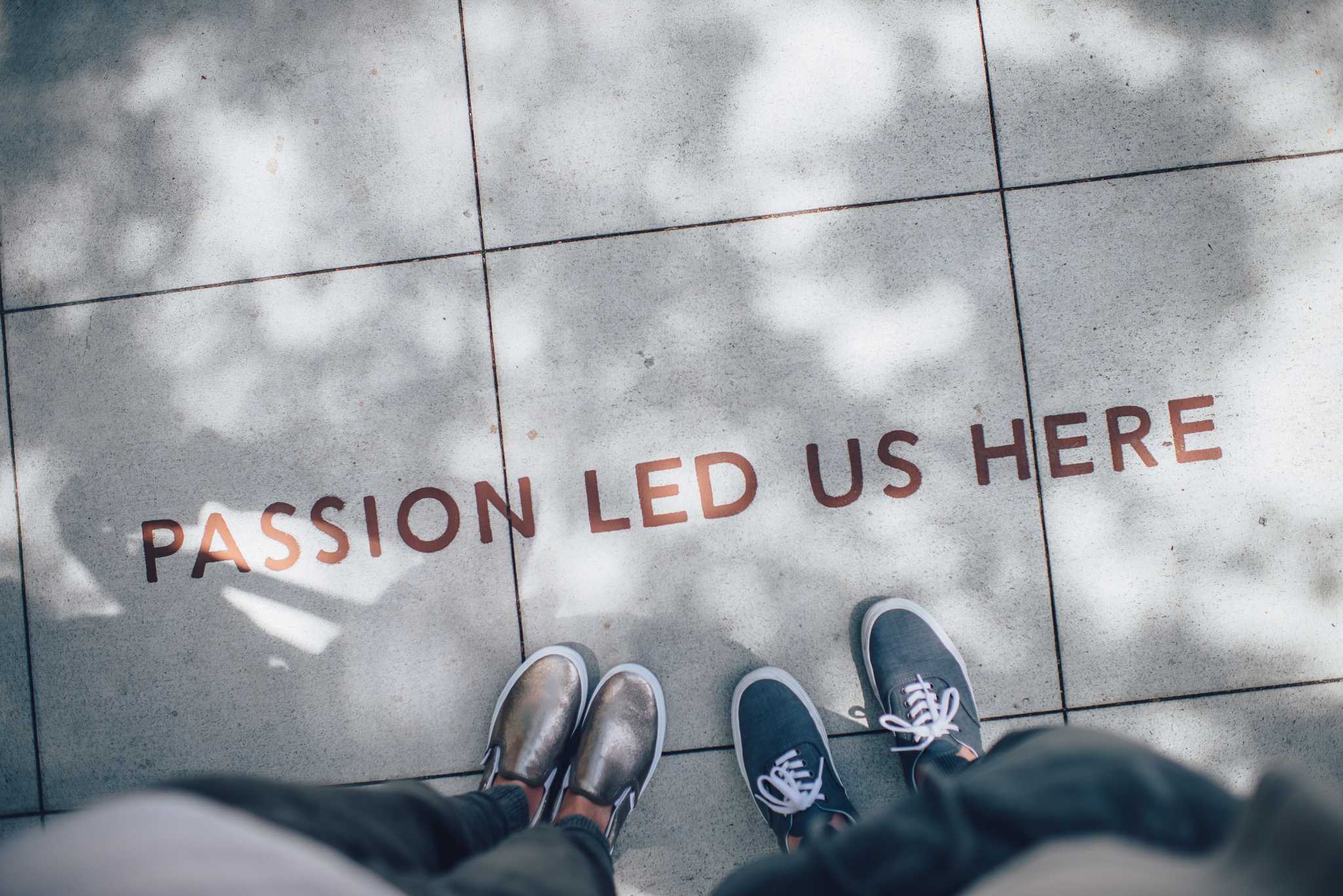 two people stand over "passion led us here" painted on the sidewalk