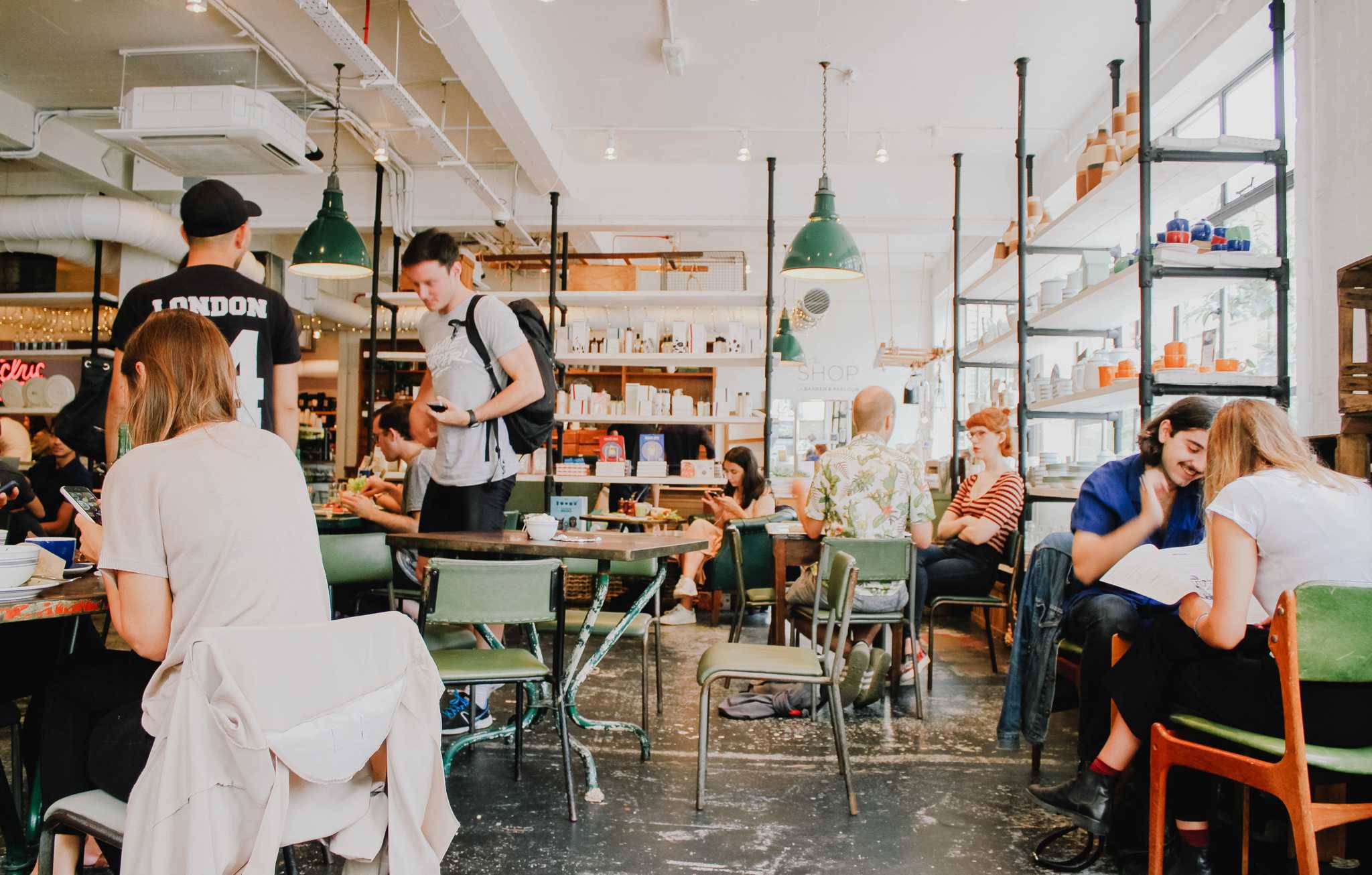 Several people sit around a cafe writing, reading, and talking